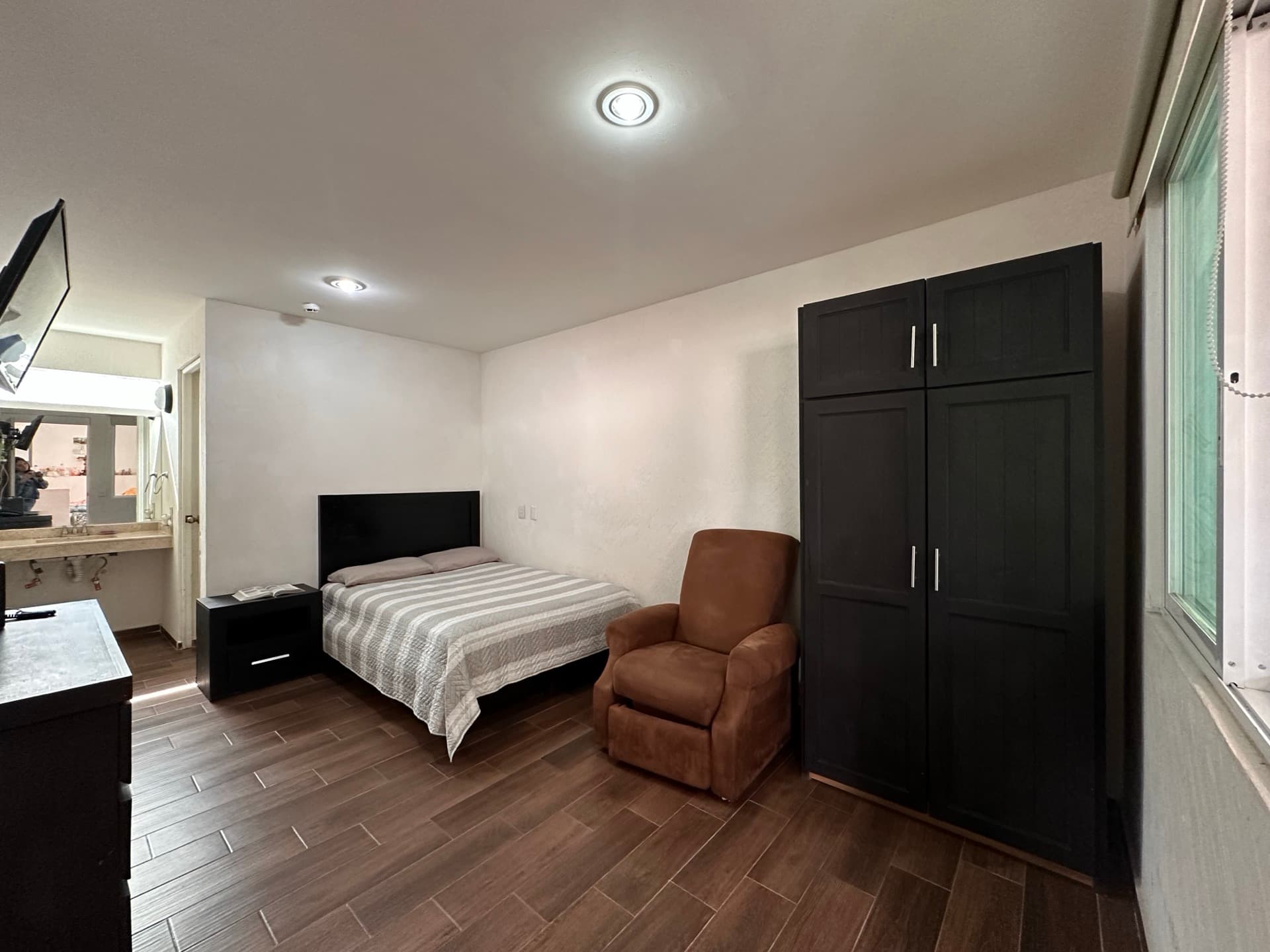 Habitación amplia con cama, sillón y clóset